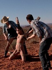 Desperate mega-bitch Amber is in need of a ride. She is out in the middle of nowhere. Completely secluded and convenient for two sadomasochistic predators Maestro and Claire to pick up a woman in need of some defiling. Once found they waste no time in priming their joy ride vagina with some tight bondage and dick sucking. She is then bound H style with wooden spikes into the warm desert sand and tortured with bands on her feet and nipple forceps roped with twine to labia clamps. After Claire and Maestro are amused, they drag this cunt bound in reverse plea thru a canyon to her next destination - straddled on a hard rock wash in the bottom of a desolate canyon. A friendly competition is created to see who is meaner with the single tail and cane then Amber's greedy holes are packed to the brim with enormous fucktoys. Eventually this cockslut is put on show bound in a kneeling spread eagle along the grand vista of the Western rock valley and is made to sate Maestro's hunger for rogue cunt.