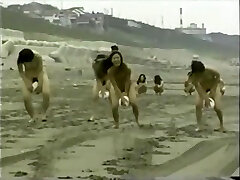 日本裸体的女孩球playnig在海滩上