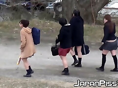 Four Asian schoolgirls fool around outside before peeing