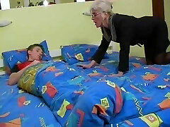 Mature with Silver Hair Glasses and Pantyhose Wakes the Boy