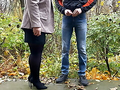 Hot milf in pantyhose and skirt holding boy's cock outdoors while pissing