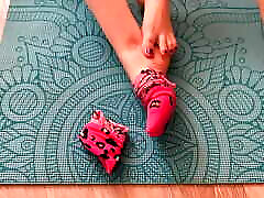 gloria gimson con calcetines rosas acaricia sus pies en una esterilla de yoga