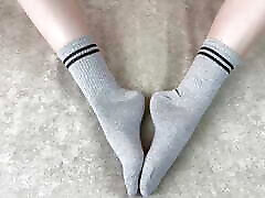 女孩在床上抚摸她的腿在灰色棉袜