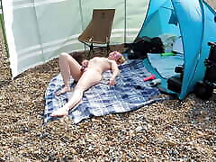 एक युवा सुनहरे बालों वाली पत्नी नग्न है और एक ब्रिटिश सार्वजनिक समुद्र तट पर