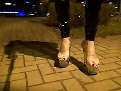 crossdresser walks on the street in transparent high heels