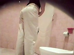 A woman wearing white jeans is pissing in the face sitting board toilet