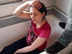 una ragazza in abiti si siede in bagno e riceve un flusso
