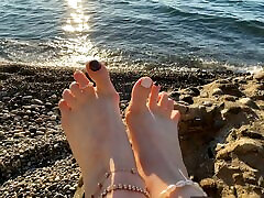 herrin lara spielt mit ihren füßen und zehen am strand