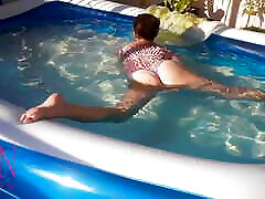 सुरुचिपूर्ण और लचीली बेब, आउटडोर स्विमिंग पूल में पानी के नीचे तैरना । स्विमिंगसुइट