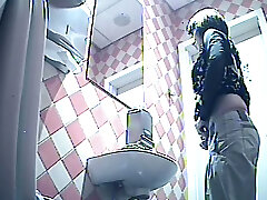 Brunette white lady in the public toilet room filmed from behind