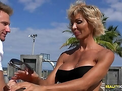 Stacked MILF in a thong at the beach penetrates a younger stud